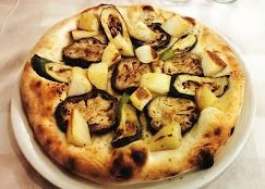 Una pizza con verdure su un piatto bianco su un tavolo.