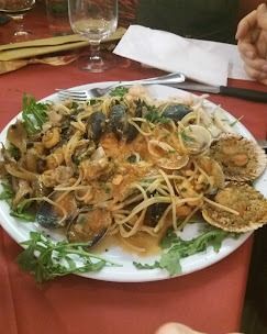 Un piatto di cibo con tagliatelle e vongole su un tavolo.