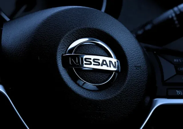 Nissan logo on a black steering wheel in a car interior