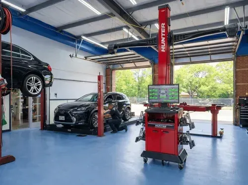 Auto repair shop with cars on lifts and a red alignment machine in the center.