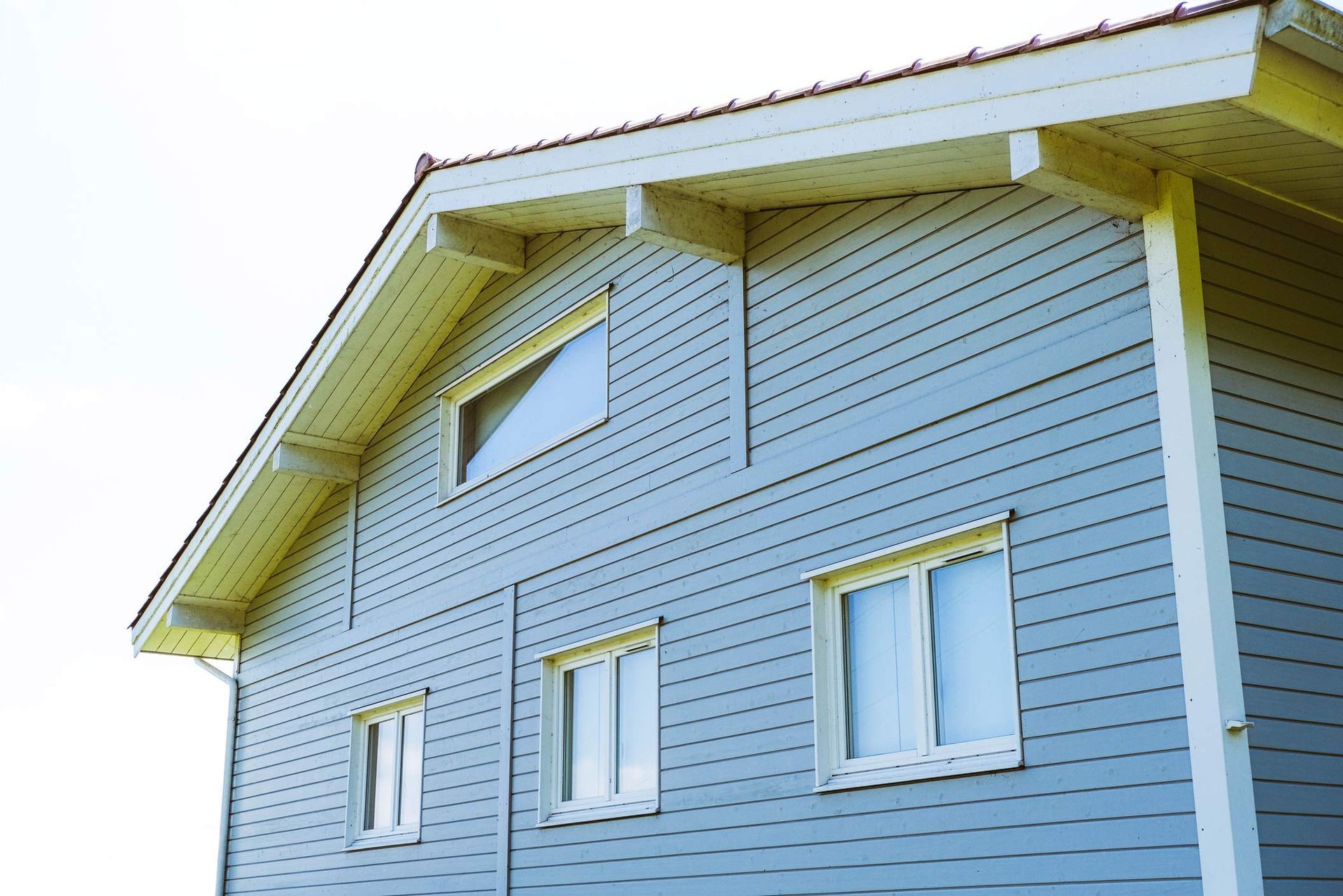 Blue siding house with white trim, three windows on lower level, one triangular window above.