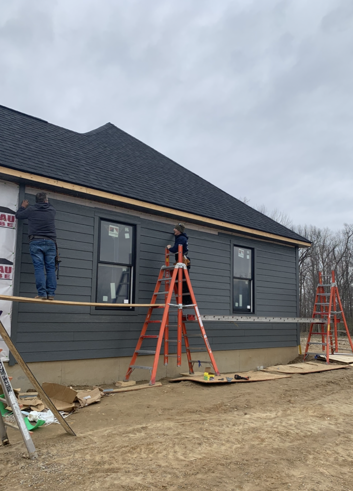 White clapboard house with green shutters and an open window.
