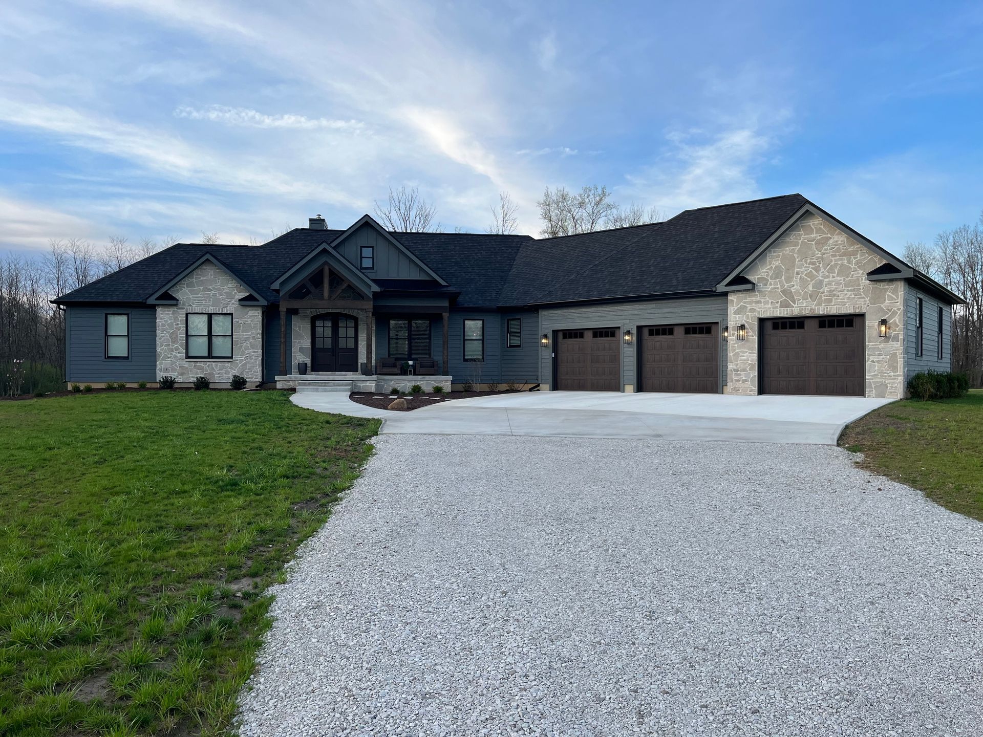 Two workers installing solar panels on a brown shingled roof under a clear sky.