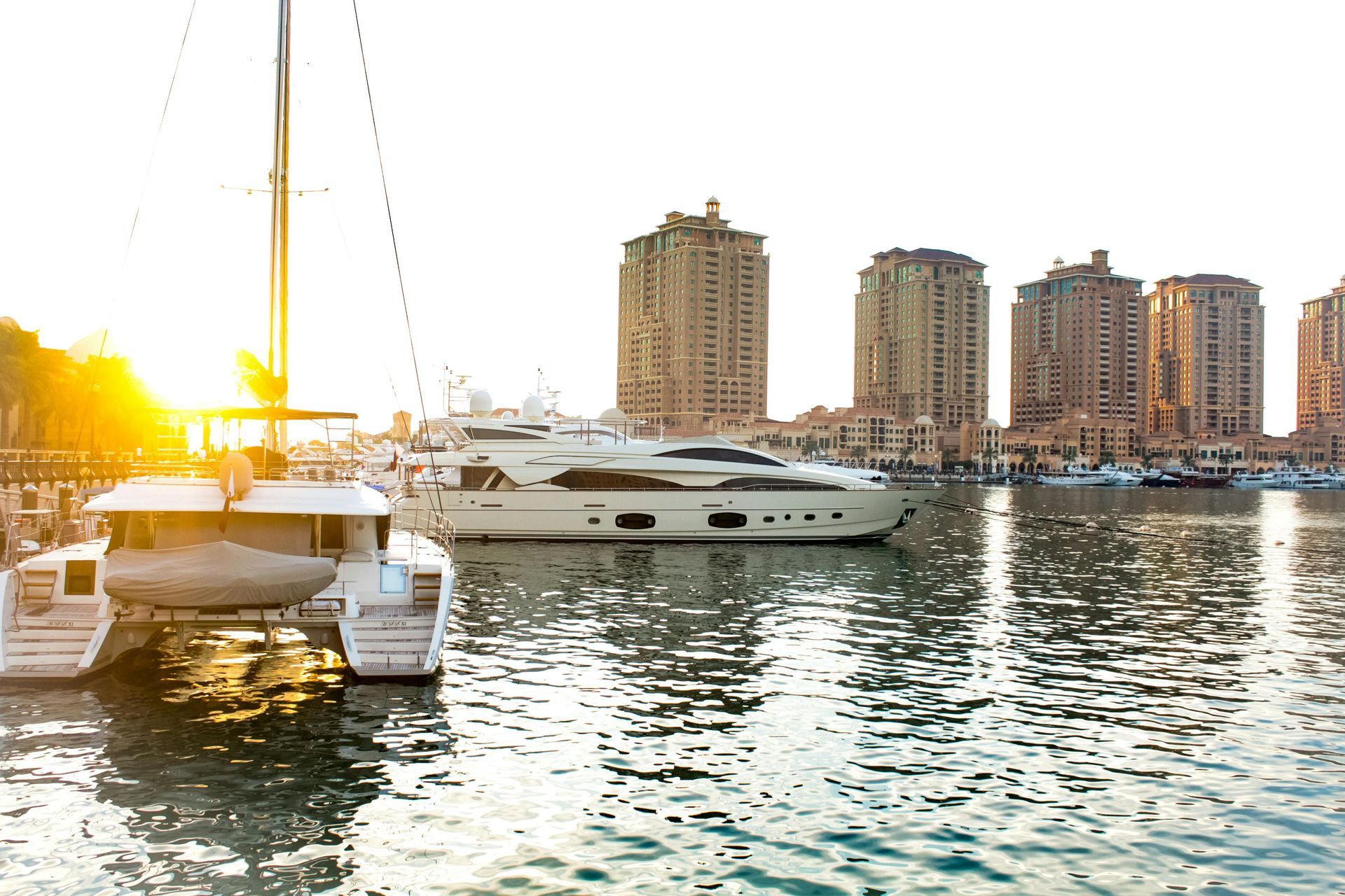 A group of boats are docked in a harbor with buildings in the background.