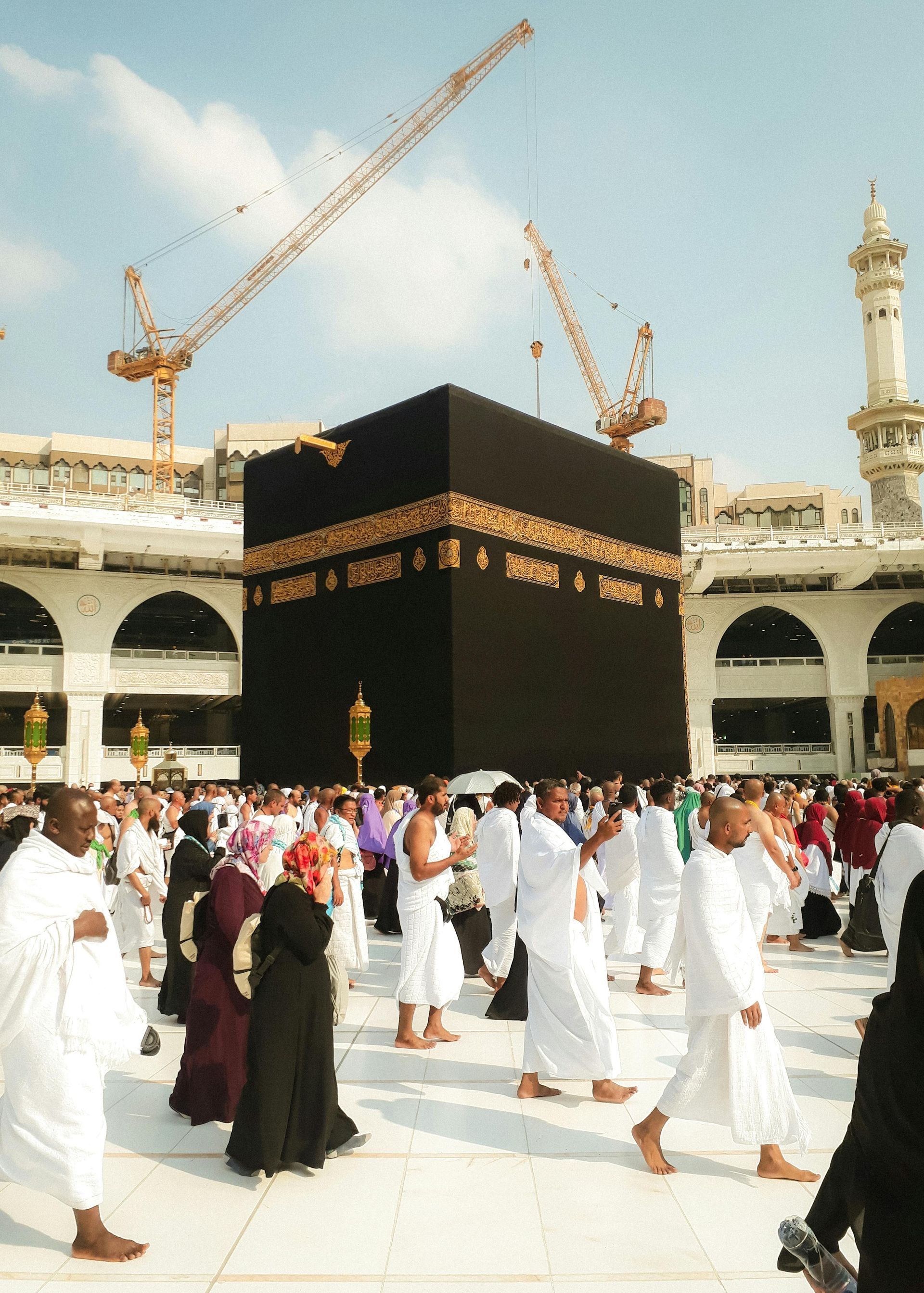 A group of people are walking in front of the kaaba