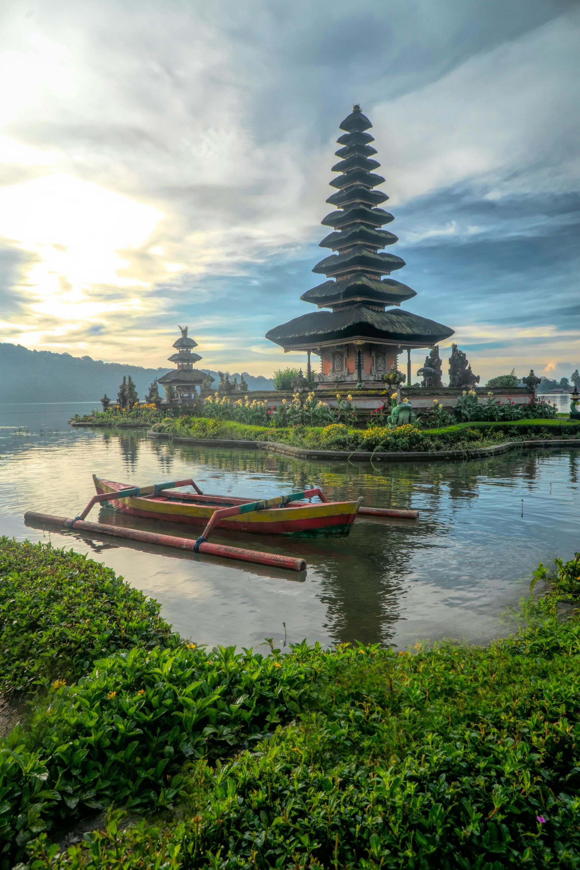 A temple on a small island in the middle of a lake with a boat in the water.