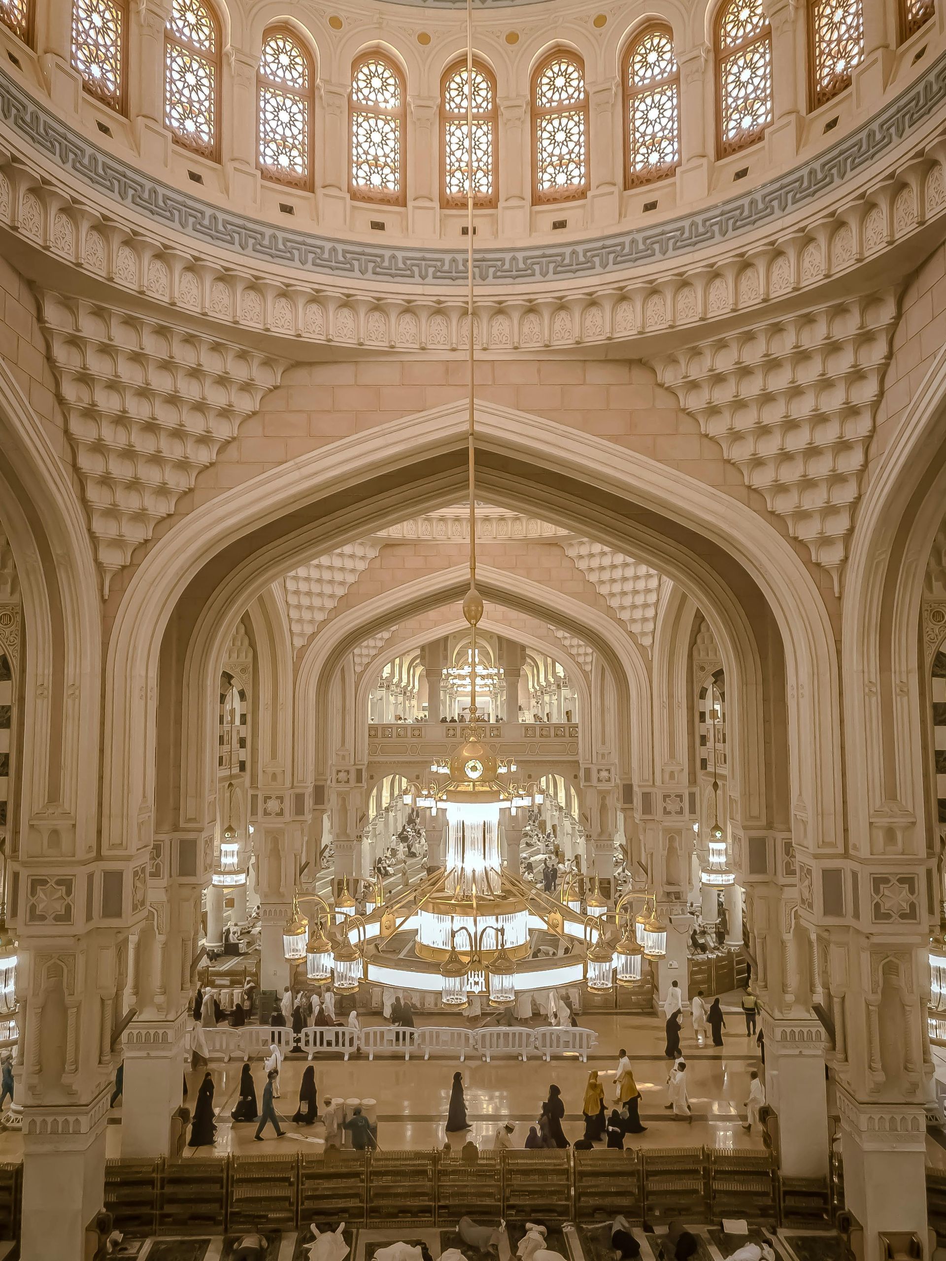 The inside of a mosque with a chandelier and stained glass windows.