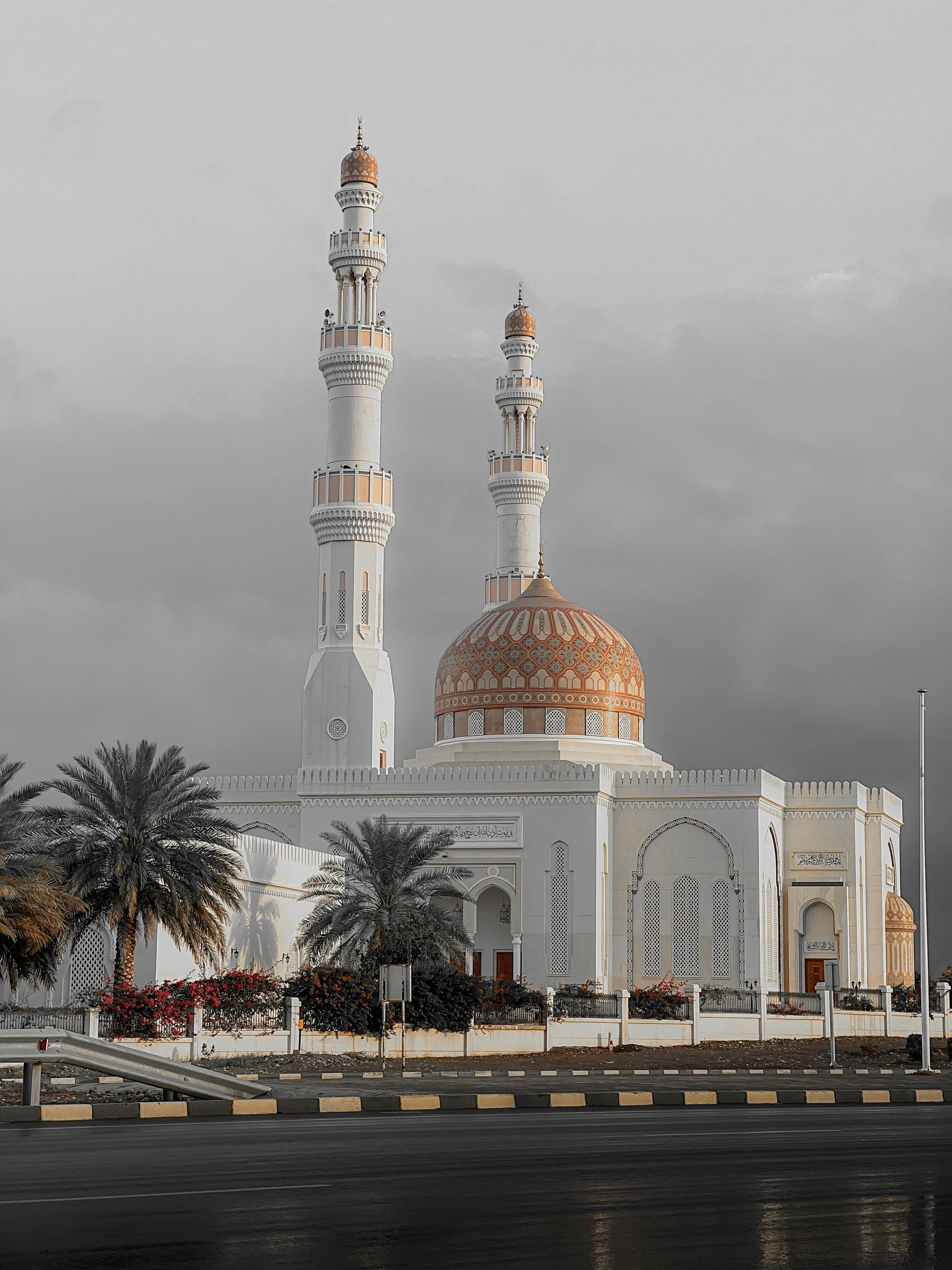 A large white mosque with two minaret 's and a dome on a cloudy day.