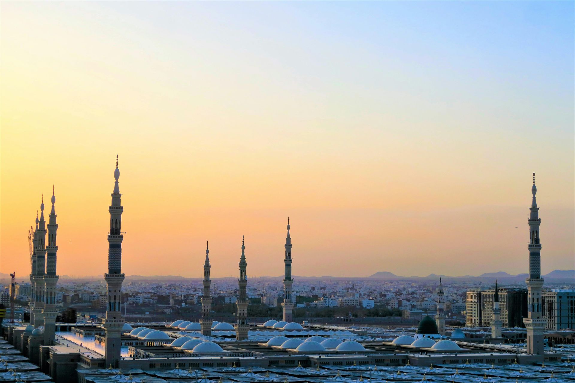 A sunset over a city with a mosque in the foreground.