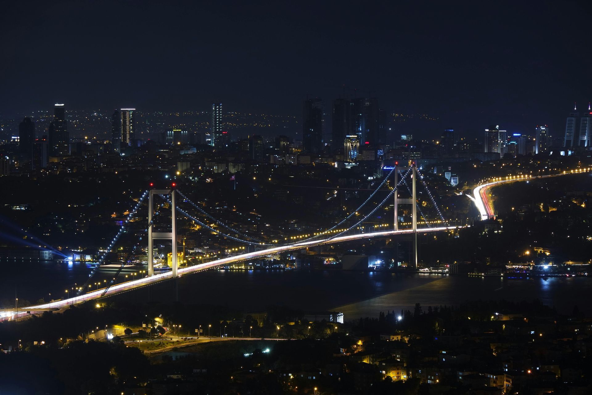 A bridge over a body of water is lit up at night