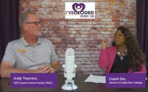 A man and a woman are sitting at a table in front of a microphone.