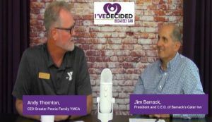 Two men are sitting at a table in front of a microphone.