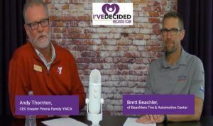 Two men are sitting at a table in front of a microphone.