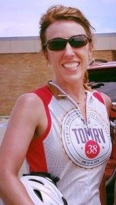 A woman wearing sunglasses and a tommy shirt is holding a helmet.