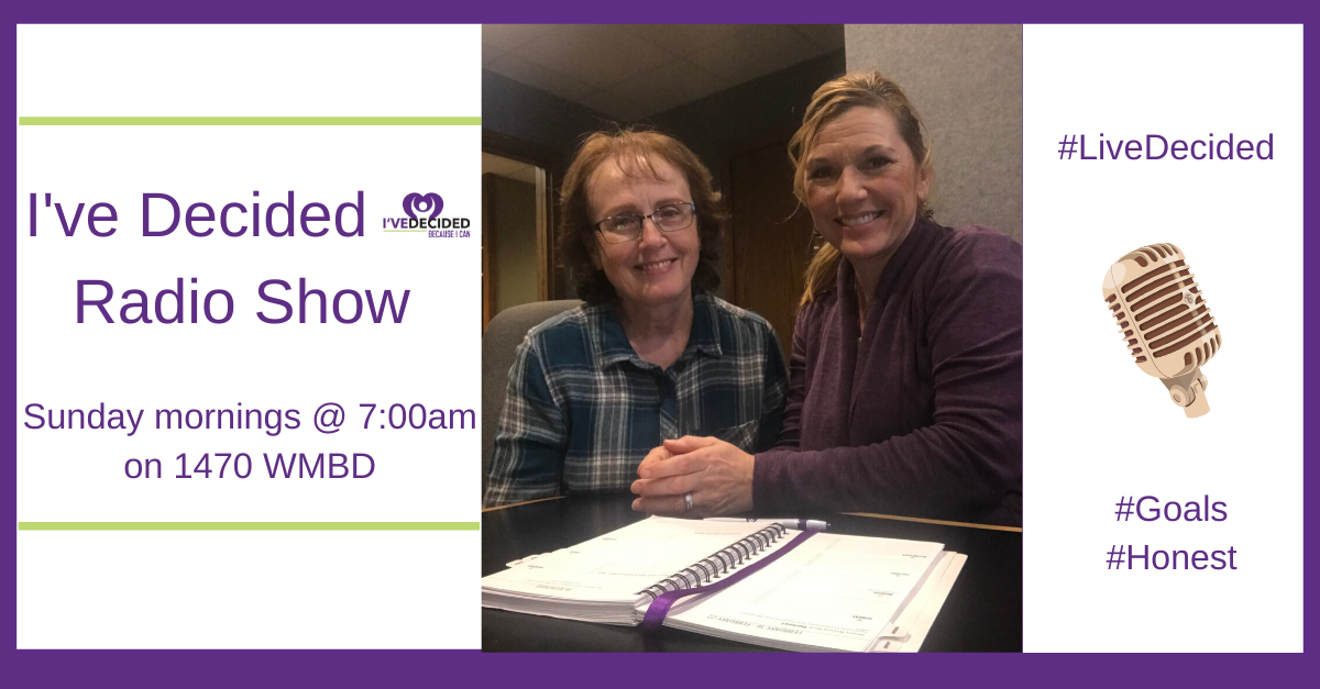 Two people are sitting at a table in front of a sign that says i 've decided radio show