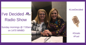 Two women are sitting at a table in front of a microphone.