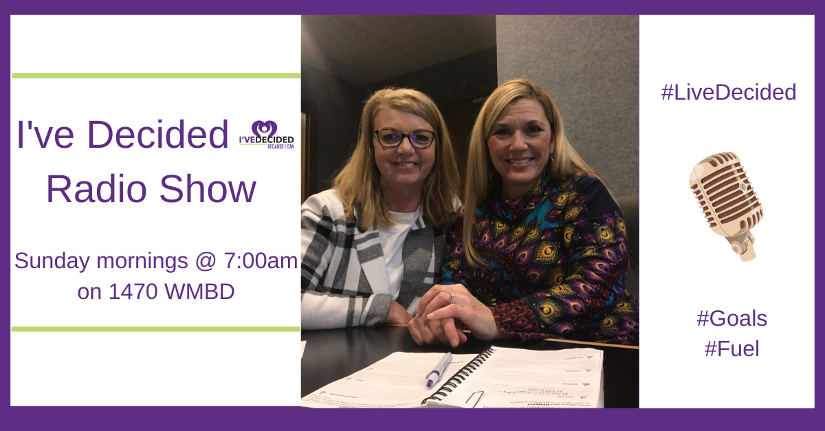 Two women are sitting at a table in front of a microphone.