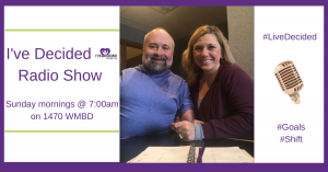 A man and a woman are sitting at a table in front of a sign that says i 've decided radio show