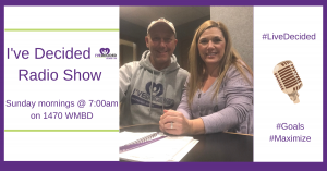 A man and a woman are sitting at a table in front of a sign that says i 've decided radio show
