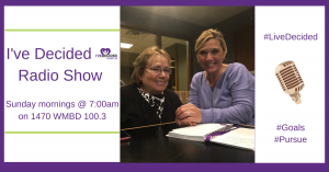 Two women are sitting at a table in front of a microphone.