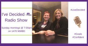 Two women are sitting at a table in front of a sign that says i 've decided radio show