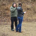 A man and a woman are standing next to each other on a dirt field.
