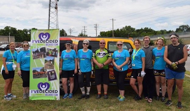 A group of people standing in front of a yellow van.