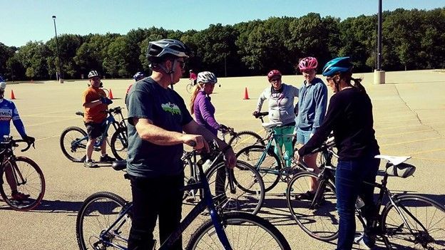 A group of people are standing around bicycles in a parking lot.