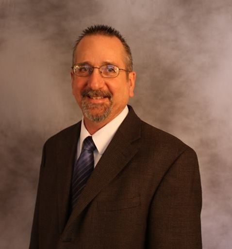 A man in a suit and tie is smiling for the camera