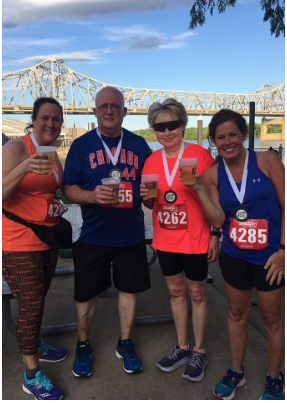 A group of runners are posing for a picture and one of them has the number 4285 on her shirt