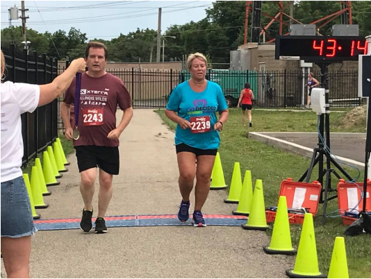 A woman is taking a picture of a man and woman running in a race.