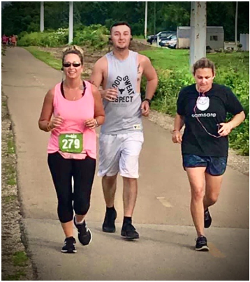 A man and two women are running on a path.