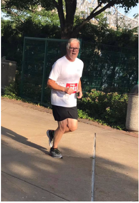 A man wearing a white shirt and black shorts is running a marathon