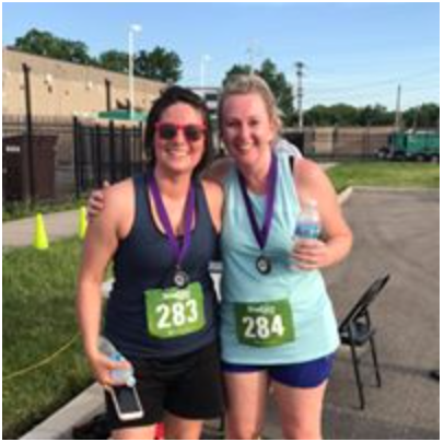 Two women are posing for a picture with medals on their shirts.