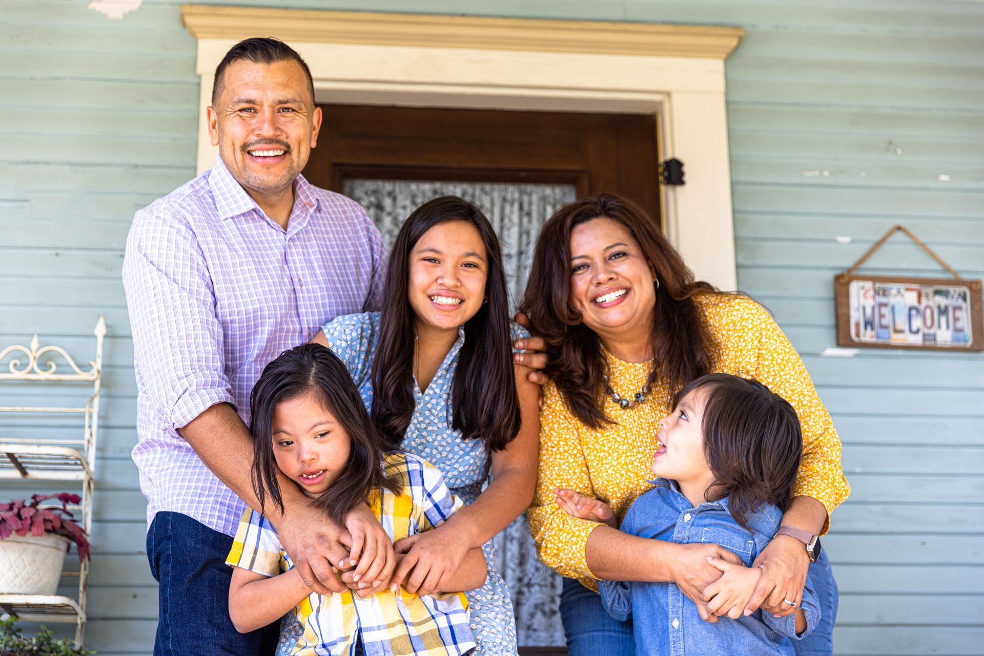 A family is posing for a picture on the porch of their house.