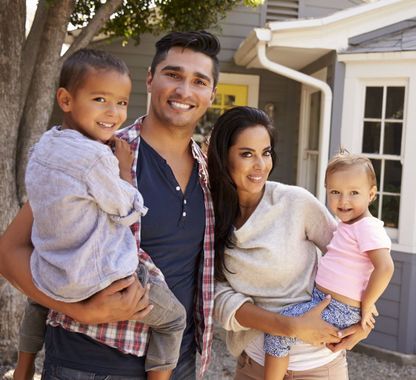 A family is posing for a picture in front of their house.