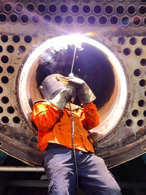 Técnico realizando el mantenimiento a un cañón de caldera industrial