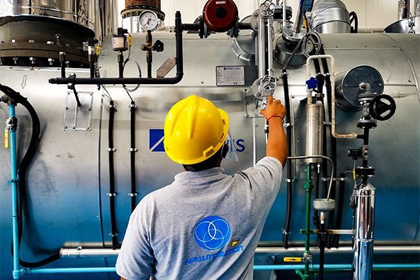 Técnico ajustando una válvula a una caldera industrial