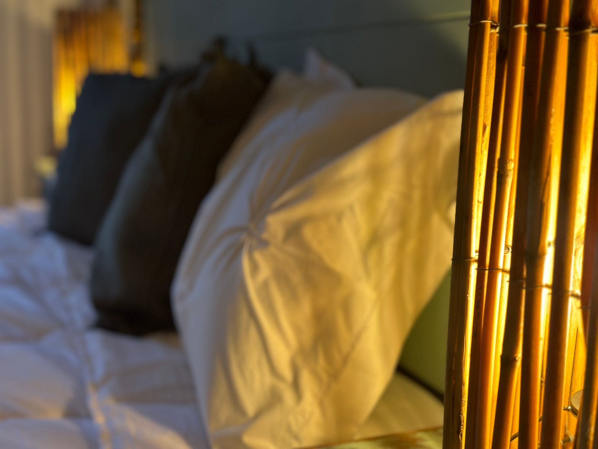 Una cama con almohadas y una lámpara en primer plano.