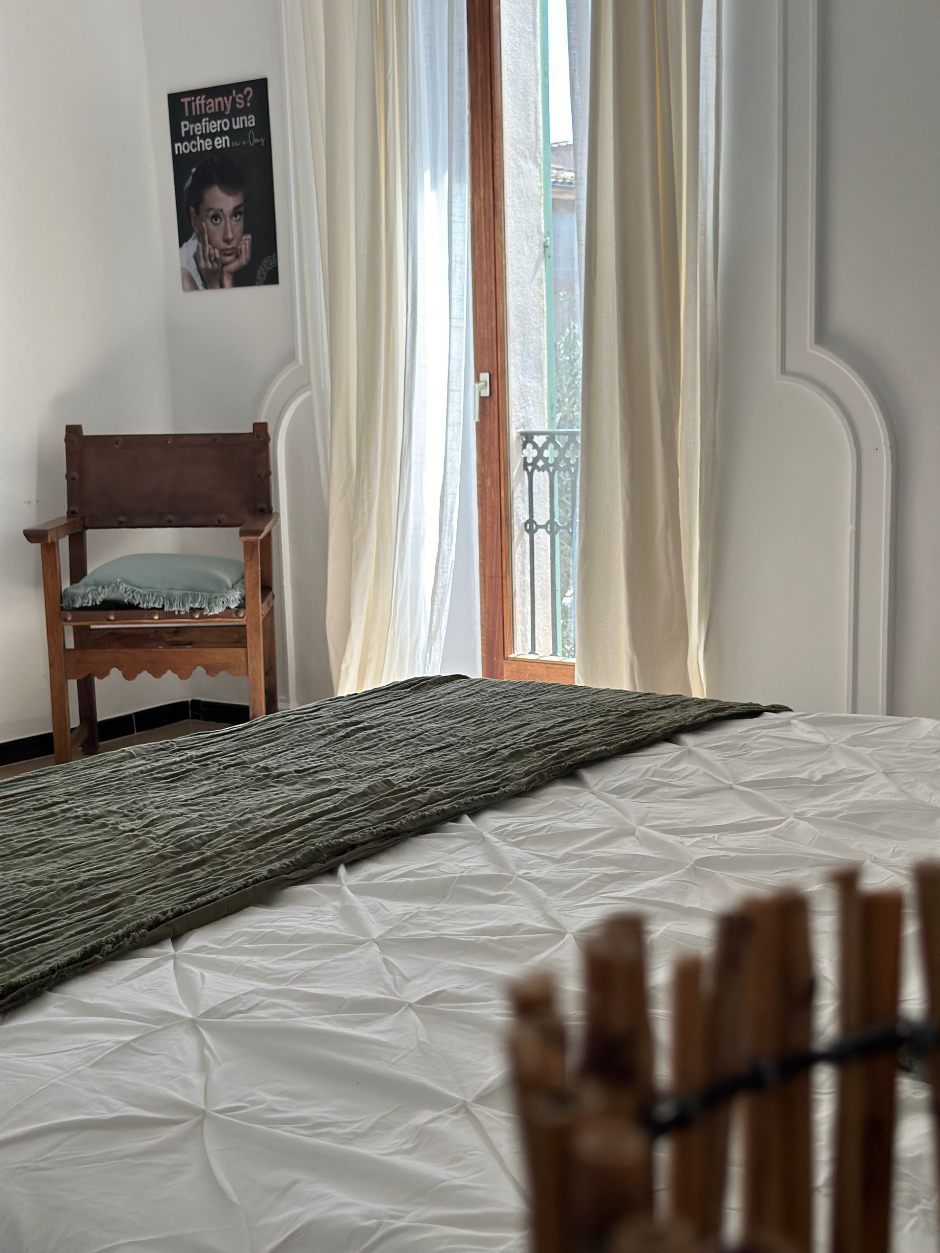 Un dormitorio con una cama, una silla y una ventana.