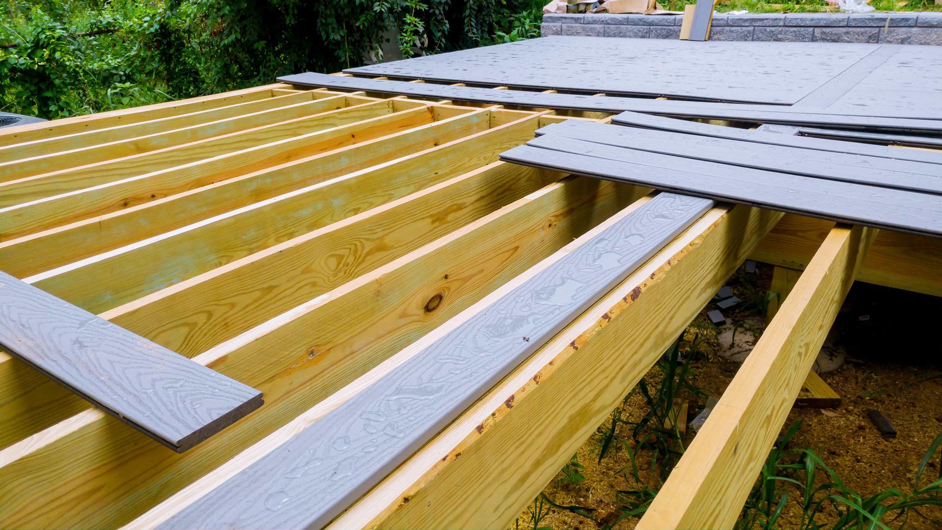 Wooden roof framing with gray metal sheets being installed on top outdoors
