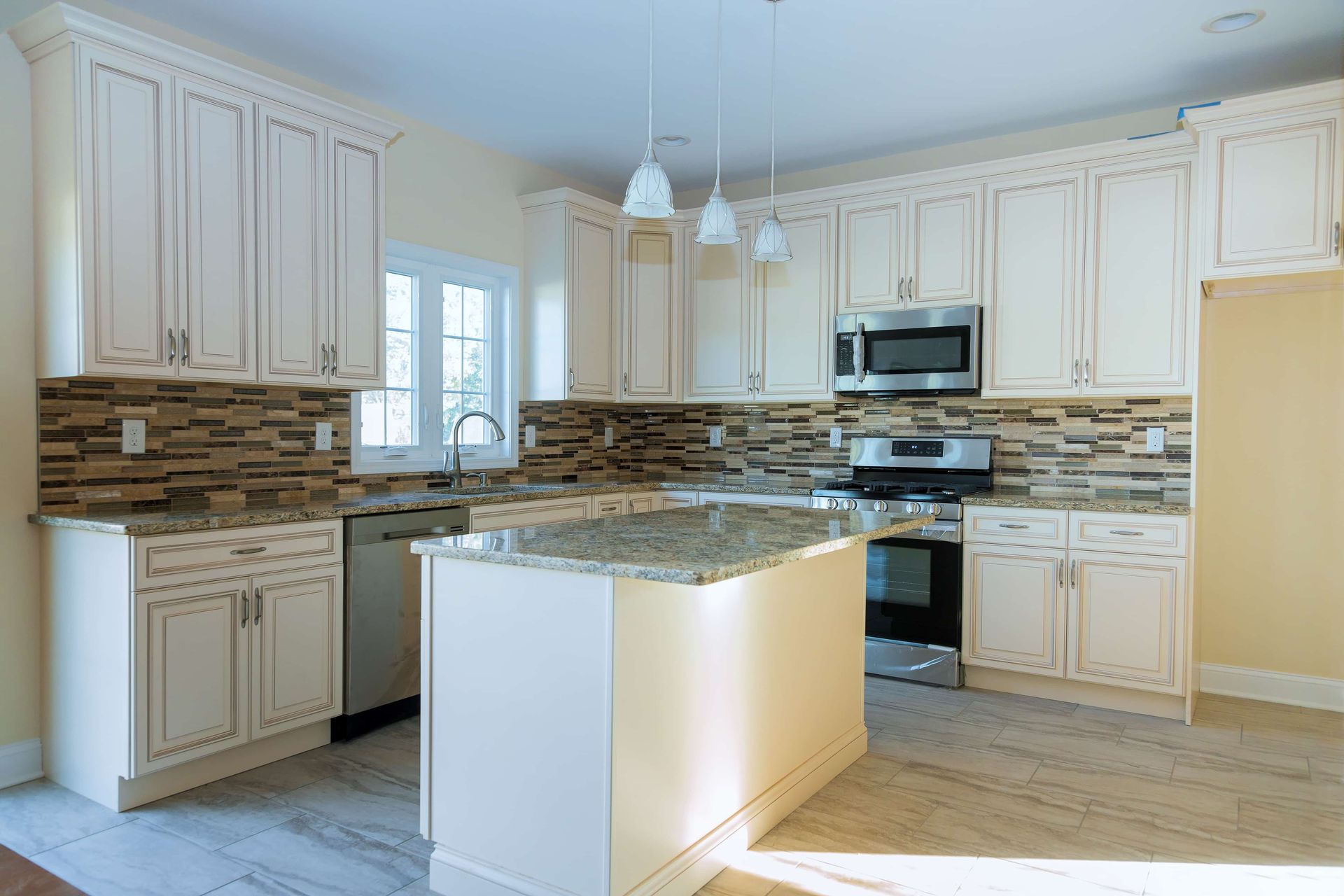 Bright modern kitchen with white cabinets, granite island, and stainless steel appliances