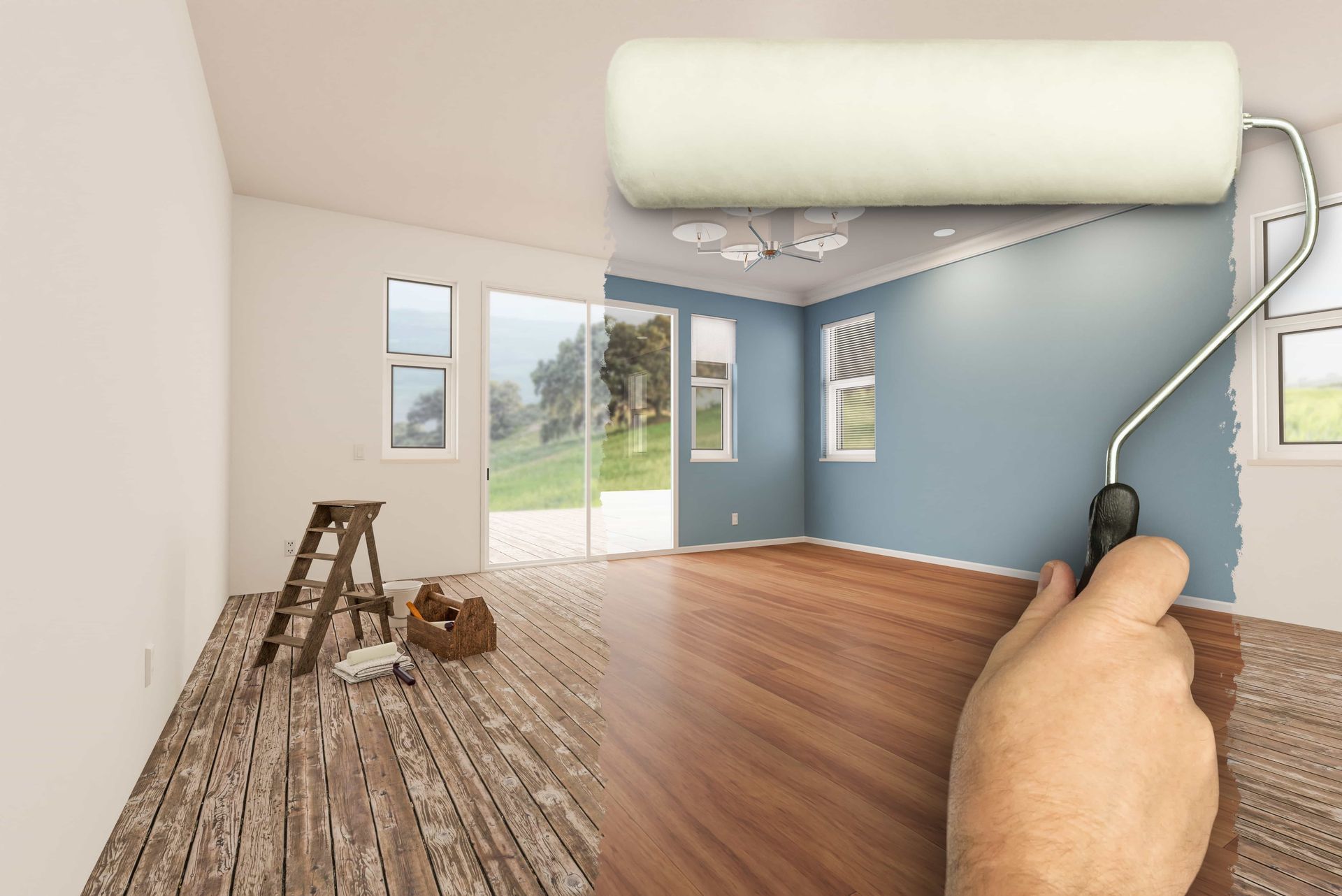 Hand holding a paint roller painting a blue wall in a room with wood floors and a ladder nearby