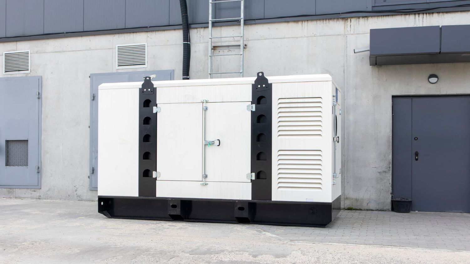A large white generator is parked in front of a building.
