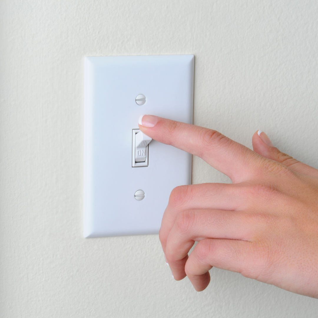 A person is pressing a light switch with their finger