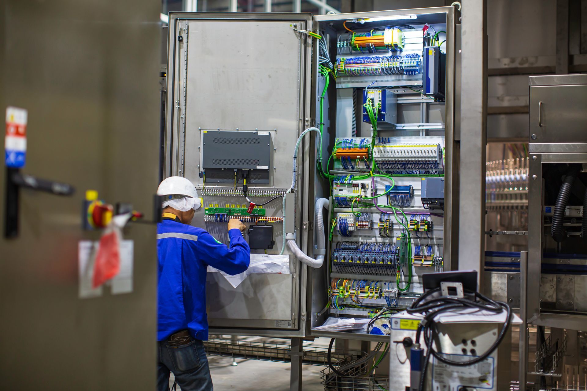 A man is working on an electrical box in a factory.