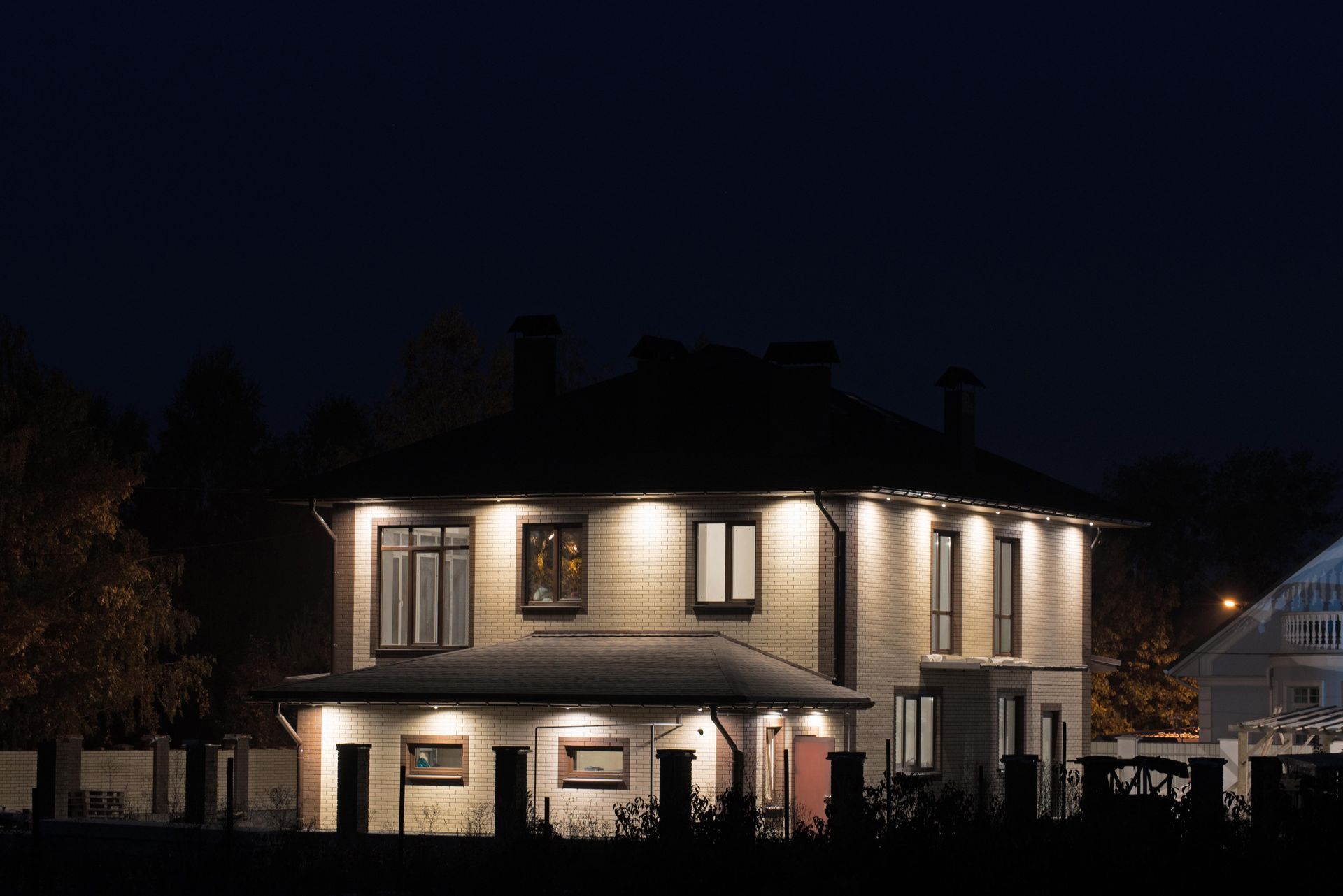 A house is lit up at night with a dark sky in the background.