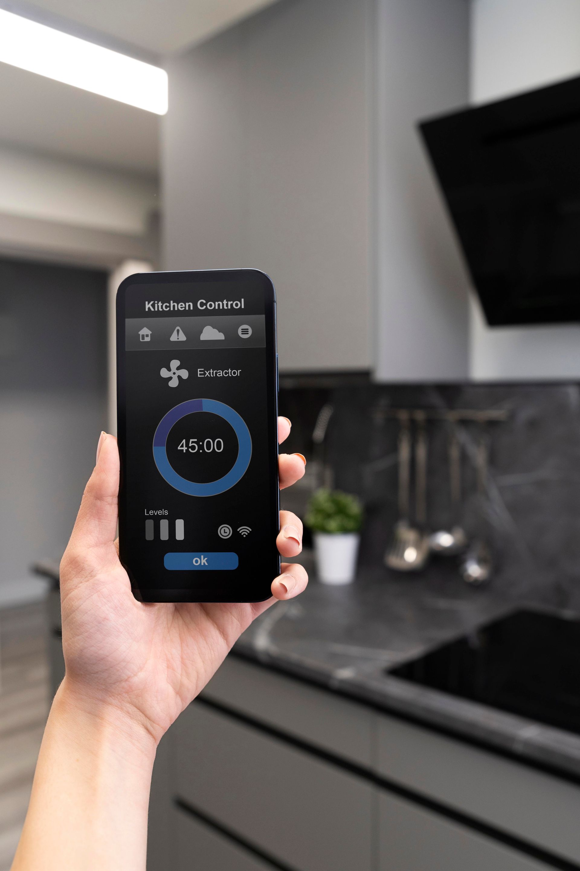 A person is holding a smart phone in their hand in a kitchen.