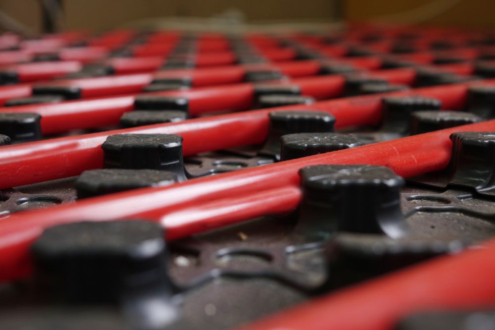 Close-up of red pipes snaking through black plastic supports, forming an underfloor heating system.
