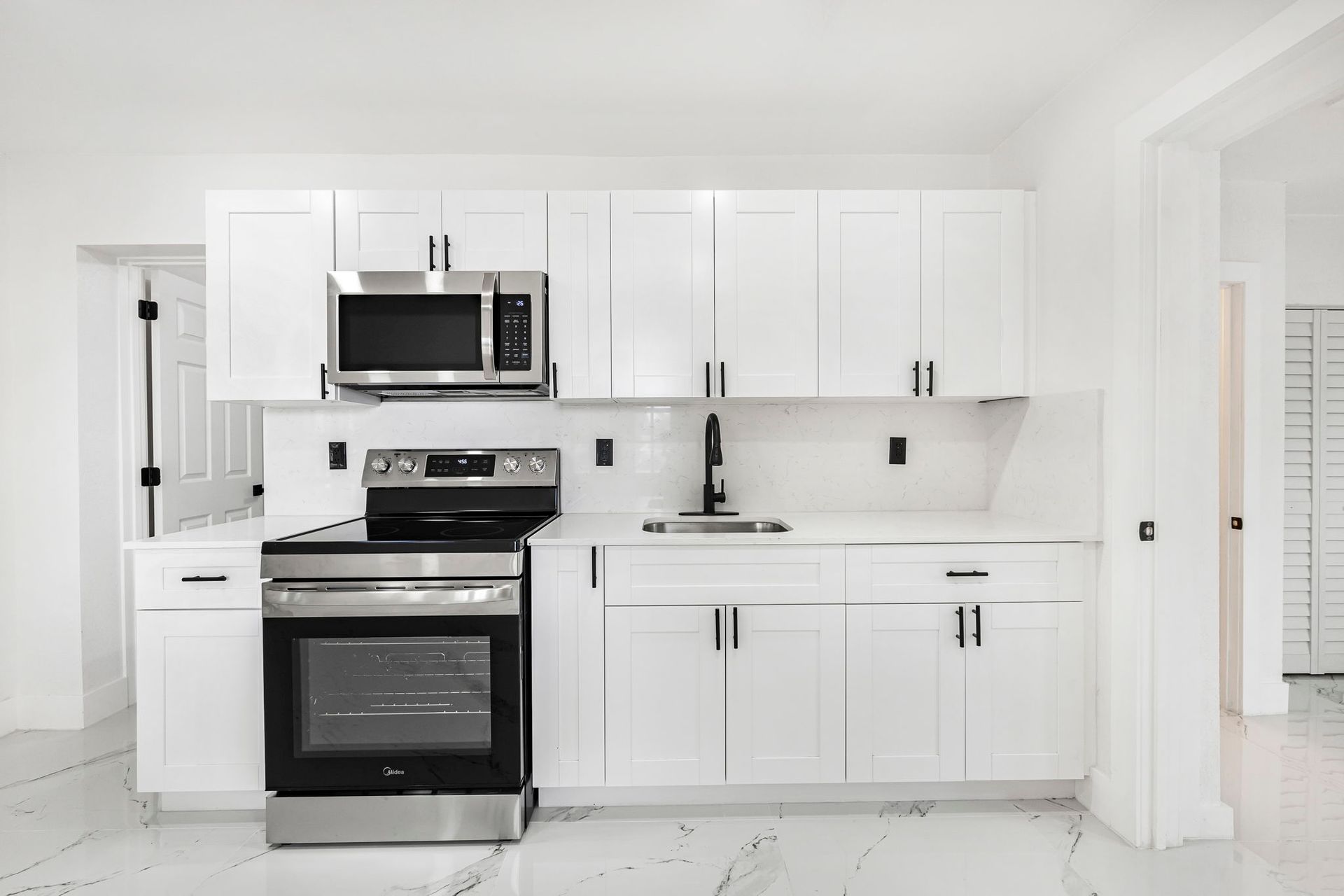White kitchen with stainless steel appliances and black accents.